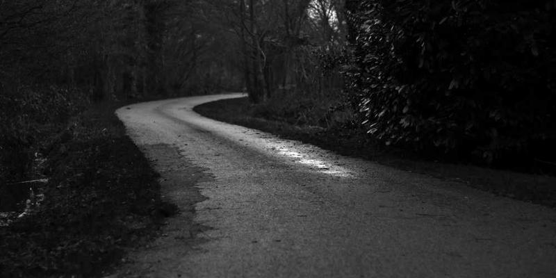 一片宁静的河畔,阳光透过树叶的缝隙洒在水面上,一个年轻女子低头将装满情书的漂流瓶投入河中,画面温馨而充满诗意。