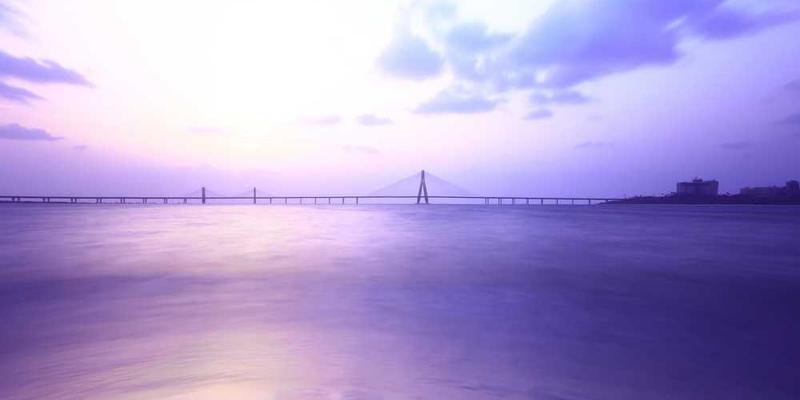 小主人大学时期的生活照,手里拿着一本书,背景是异国他乡的风景